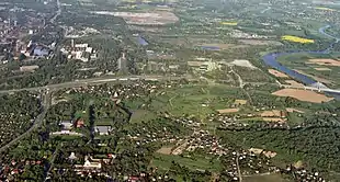 Photographie aérienne d'une zone urbaine peu dense sur laquelle est visible, au tout premier plan, un monastère.