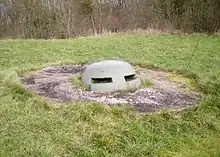 dome de béton dépassant légèrement du sol au milieu d'une pelouse