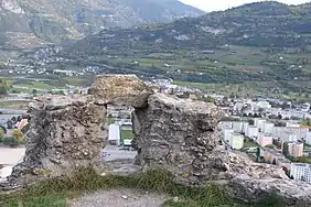 Petit mur en pierre partiellement détruit. Au centre de celui-ci se trouve un trou.