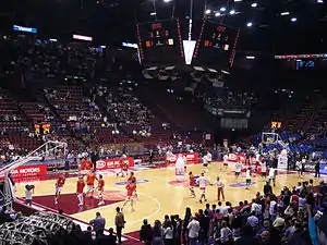 vue de l'intérieur de la salle du Mediolanum Forum, deux équipes de basket-ball étant à l’échauffement.