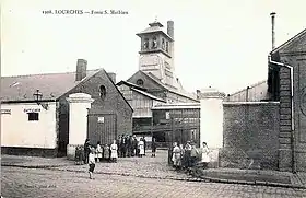 Carte postale ancienne en noir et blanc de la fosse Saint-Mathieu des mines de Douchy à Lourches avec son chevalement recouvert en bois, ses bâtiments divers, et son entrée.