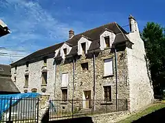 Le logis de l'ancienne ferme à côté de l'église Saint-Étienne, sur la Grande-Rue, au village. La tente dans la cour protège du mobilier céramique sorti de fouille.