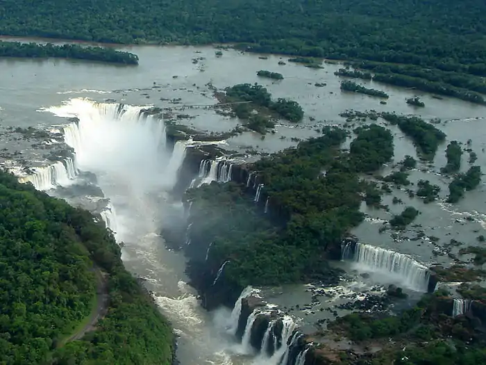 Vue aérienne des chutes de l'Iguazú. Le territoire brésilien se trouve dans la partie inférieure gauche. On remarque que la largeur des chutes argentines est nettement supérieure. Au centre, les îlots de verdure font partie du territoire argentin. Au centre-gauche, la Garganta del Diablo (Gorge du Diable) fait office de frontière.