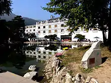 Un bâtiment blanc se reflète dans l'eau d'un lac, dans un cadre champêtre.