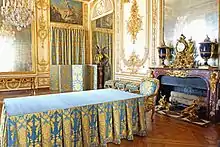 Photo d'une pièce avec un parquet en bois, une cheminée, de grands miroirs, des peintures et des boiseries dorées