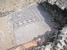 Mosaïque antique au sol, partiellement détruite au passage d'une rue.