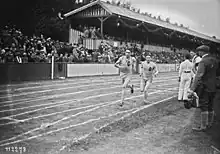 Photographie en noir et blanc de deux coureurs à pied lors d'une course dans un stade.