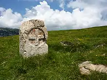 Borne en pierre avec sur sa face la plus visible une croix inscrite dans un cercle en bas-relief.