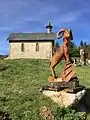 Sculpture en bois du mouflon (l'animal emblématique des Cévennes) et la chapelle protestante du village de L'Espérou, à proximité de la route départementale « D986 » en direction du Col de la Serreyrède.