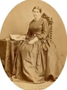 Photo monochrome d'une femme assise, la main posée sur un livre