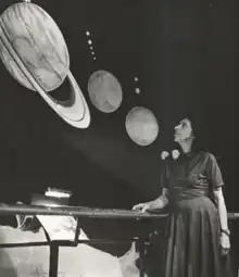 White woman standing, looking up at an astronomy exhibit.