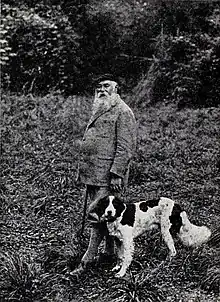 Photographie de Francis Jammes en costume de chasse, avec son chien.