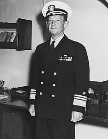 Portrait d'un homme en costume d'amiral dans un bureau.