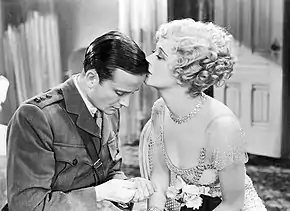 Photographie en noir et blanc du film Cavalcade de Frank Lloyd, sorti en 1933. L'image montre l'acteur Frank Lawton et l'actrice Ursula Jeans dans un dialogue amoureux.