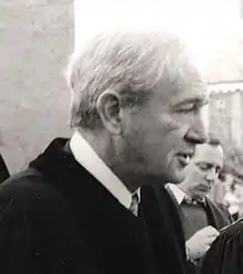 Un homme aux cheveux blancs et en costume noir