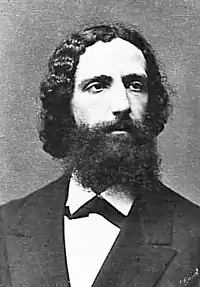 Photographie en noir et blanc, buste d'homme à barbe fournie et cheveux noirs
