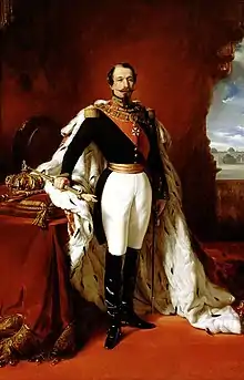 Portrait peint de Napoléon III debout, en uniforme militaire, avec les insignes de la Légion d'honneur et un manteau d'hermine sur ses épaules. Il tient la main de justice et une épée. Une couronne et un sceptre sont posés derrière lui.