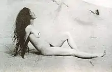 Louise Bryan de profil; nue sur une plage, se chauffant au soleil, cheveux longs non coiffés