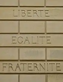 Devise française « liberté, égalité, fraternité » gravée sur un mur.