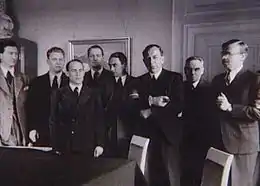 Photo noir et blanc des membres du conseil posant debout dans une pièce.