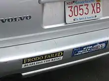Le pare-choc arrière d'une voiture de couleur grise portant plusieurs autocollants avec des inscriptions humoristiques