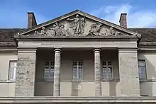 Photographie en couleur du fronton d'un bâtiment, soutenu par des colonnes.