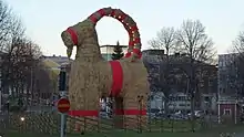 bouc en paille d’une dizaine de mètres de haut, orné de tissu rouge décoratif