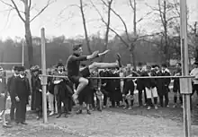 Photographie en noir et blanc d'un homme sautant au-dessus d'une barre.