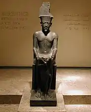 Statue acéphale du pharaon Horemheb devant le dieu Amon