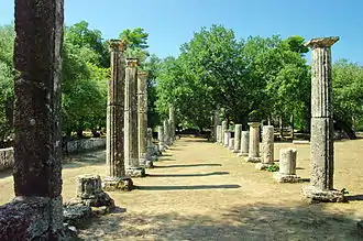 photographie couleurs d'un espace en terre battue au milieu de colonnes.