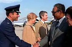 Rencontre entre un chef d'État en costume et un officier en uniforme qui se serrent la main.
