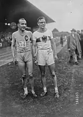 Photographie de deux athlètes se tenant la main dans un stade.