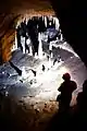 Homme debout dans une galerie souterraine avec stalagmites et stalactites