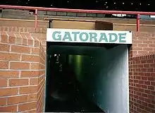 Entrée d'un couloir sous une tribune, formant un tunnel sur lequel est écrit à l'entrée « Gatorade ».