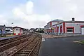 Intérieur de la gare avec le bâtiment voyageurs et le quai central et son abri.