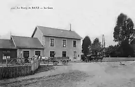 Carte postale ancienne montrant un bâtiment de deux étages accolé à une maisonnette. Deux carrioles à cheval attendent devant.