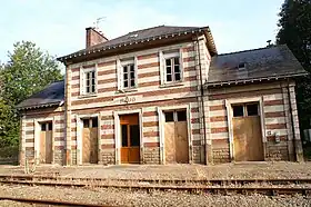 Photographie en couleurs de la façade d’une gare prise depuis la voie ferrée.