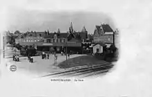 intérieur de la gare, vers 1900, avec personnages et locomotive à vapeur, au premier plan la ligne à double voies