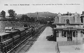 Carte postale en noir et blanc des voies et du bâtiment, avec un train à quai, vus depuis la passerelle.
