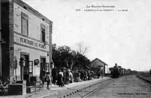 Bâtiment voyageurs, quai, voie et un train vapeur entrant en gare vers 1900