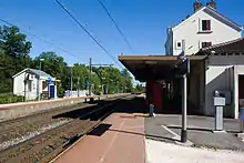 vue d'ensemble de l'intérieur de la gare avec le bâtiment voyageurs, son quai, les deux voies et le quai de la direction de Melun avec un abri voyageurs