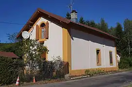 Petit bâtiment en brique et crépi, peint avec de petites ouvertures arrondies, devenu une maison.