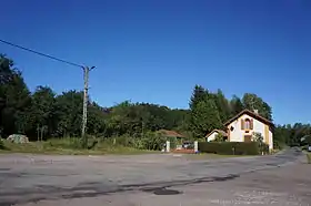 Deux petits bâtiments transformés en maison devant un bois.