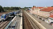 Voies, quais et bâtiment voyageurs de la gare, vus par temps ensoleillé.