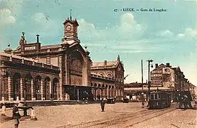 La gare avec publicités murales, tram et fontaine Montefiore.