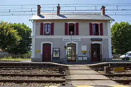 Le bâtiment voyageurs vu des voies et le passage piéton planchéié.