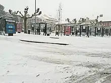 Photographie en couleurs de plusieurs arrêts de bus sous la neige.