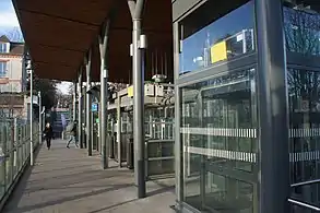 Cliché couleur. Sur la droite d'un passage piétons protégé par des balustrades se trouvent des ascenseurs.
