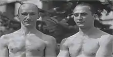 Photographie noir et blanc de deux hommes en buste torse nu.