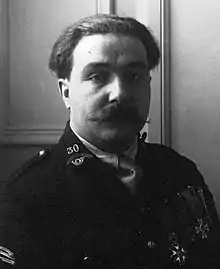 Portrait en buste, de trois-quart face, d'un homme en tenue militaire portant une moustache.